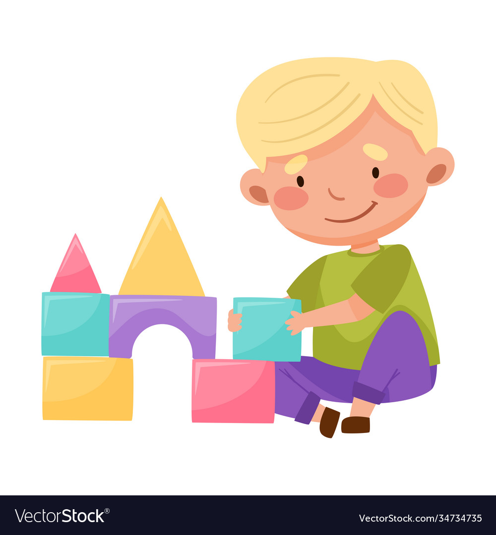 Cheerful boy building castle with tower from