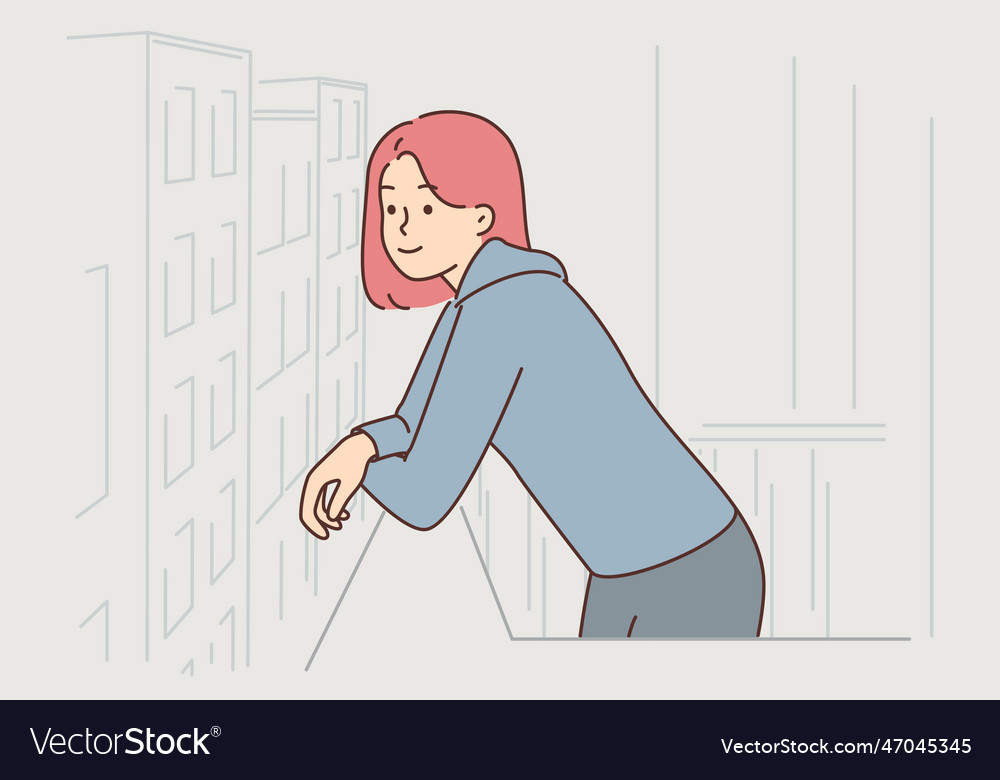 Young woman stands on balcony and admires city