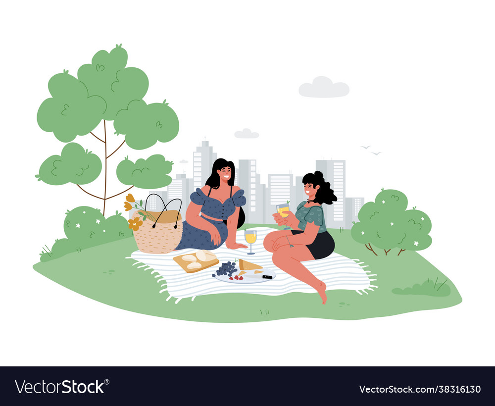 Two girlfriends sit in a city park on blanket