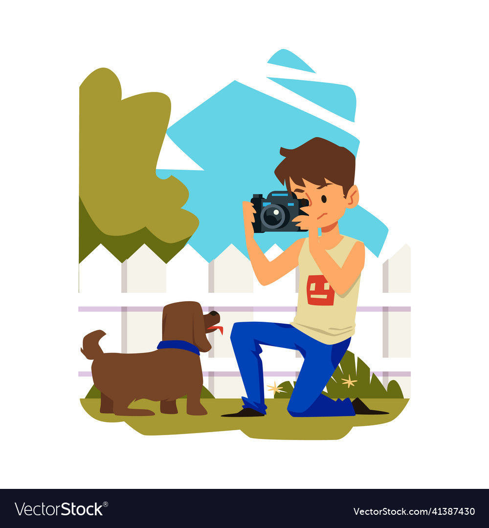 Boy with camera photographing dog in the backyard